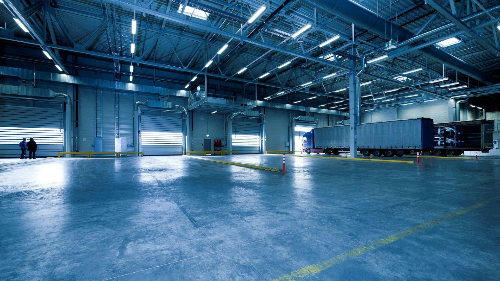 A spacious commercial warehouse with roll-up garage doors for loading and unloading.