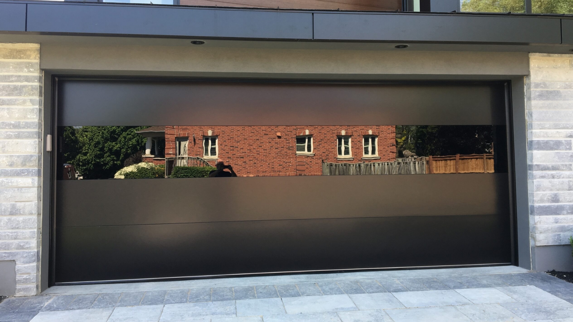 Full view of a modern garage door installed with reflective glass panels on a residential home.