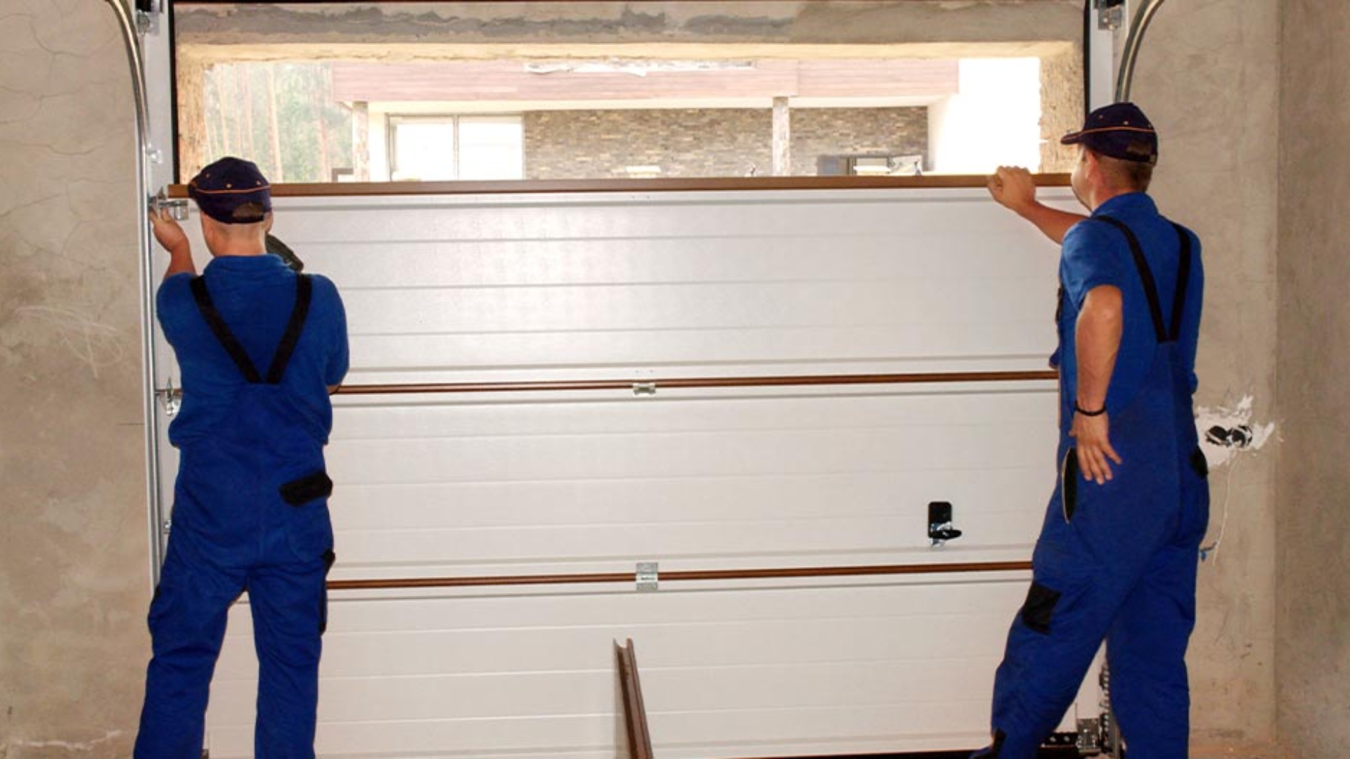 Two technicians installing a new steel garage door in a home