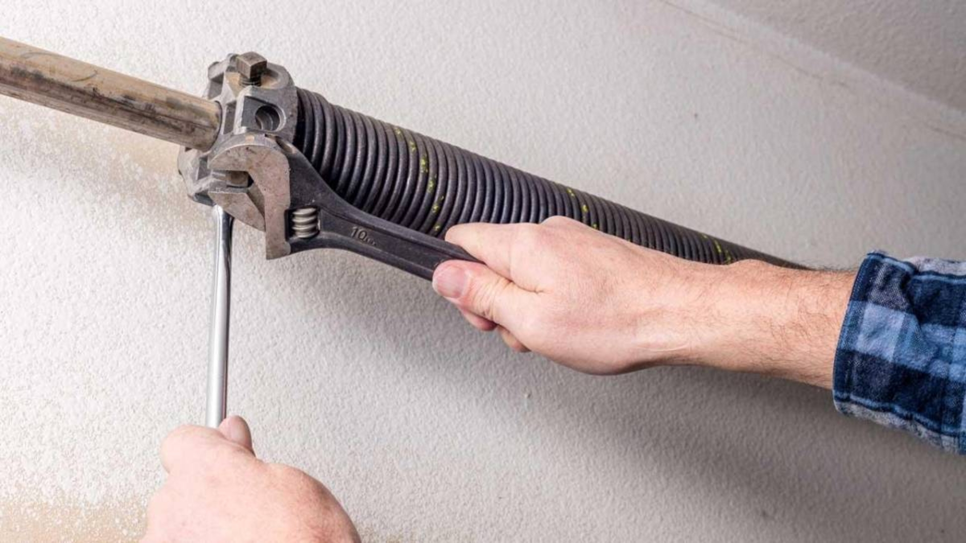 A professional technician tightening a torsion spring during garage spring repair