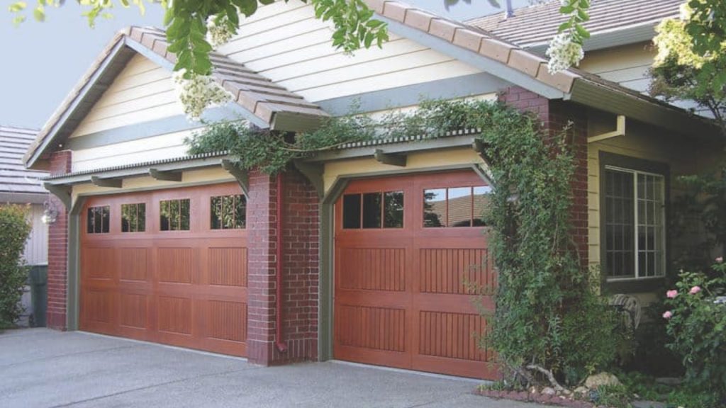 A traditional wooden garage door type with windows on a brick home in Houston