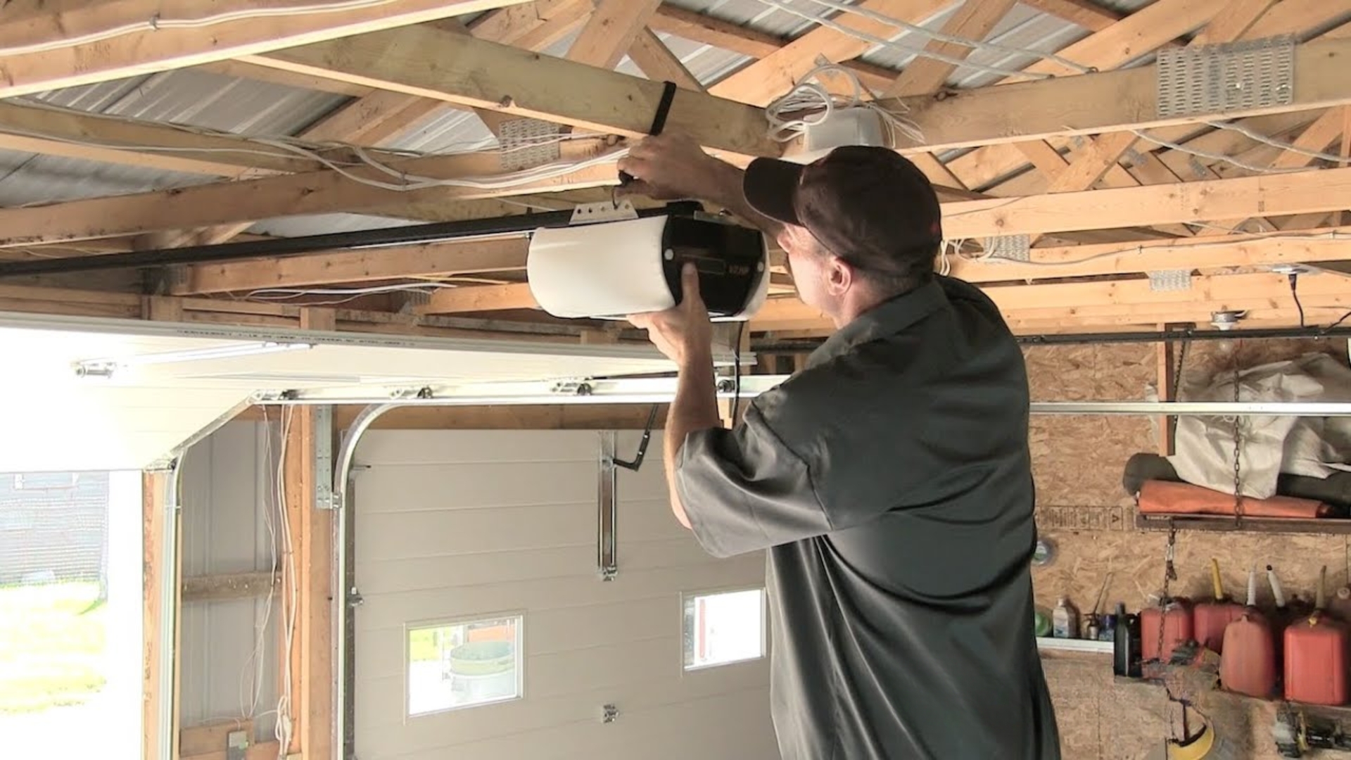 A garage door technician inspecting and testing an automatic opener in a residential garage